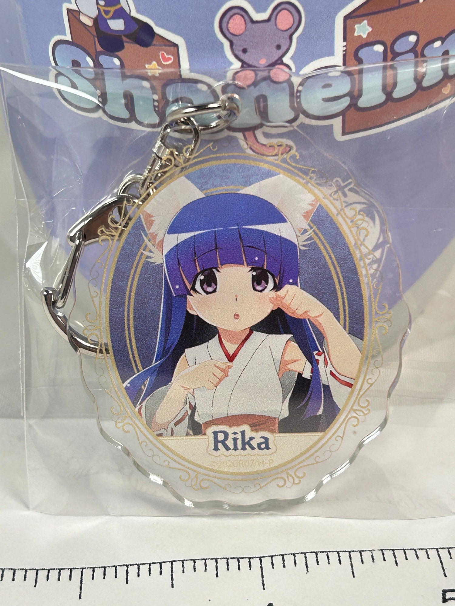 Rika Furude with cat ears on a white and blue acrylic keychain for the When they cry Collection page